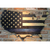 thin blue line flag on wood hanging on brick wall with light shining